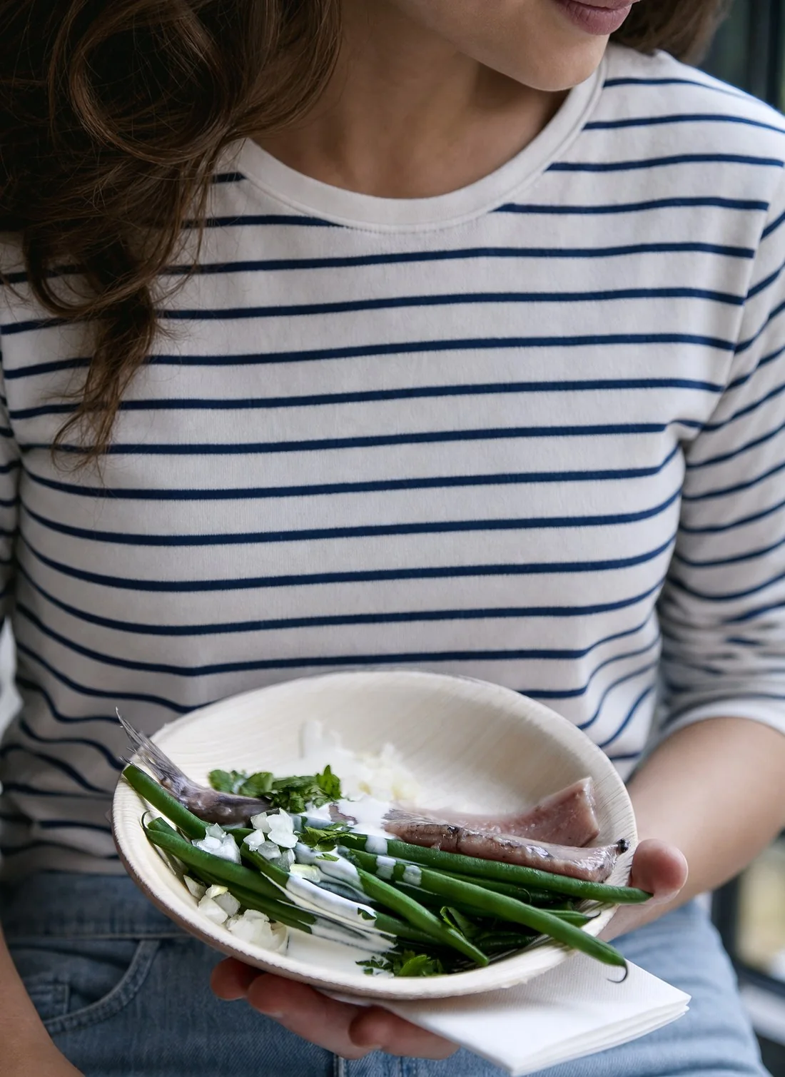 Generated: a woman in a striped shirt holds the same plate of herring