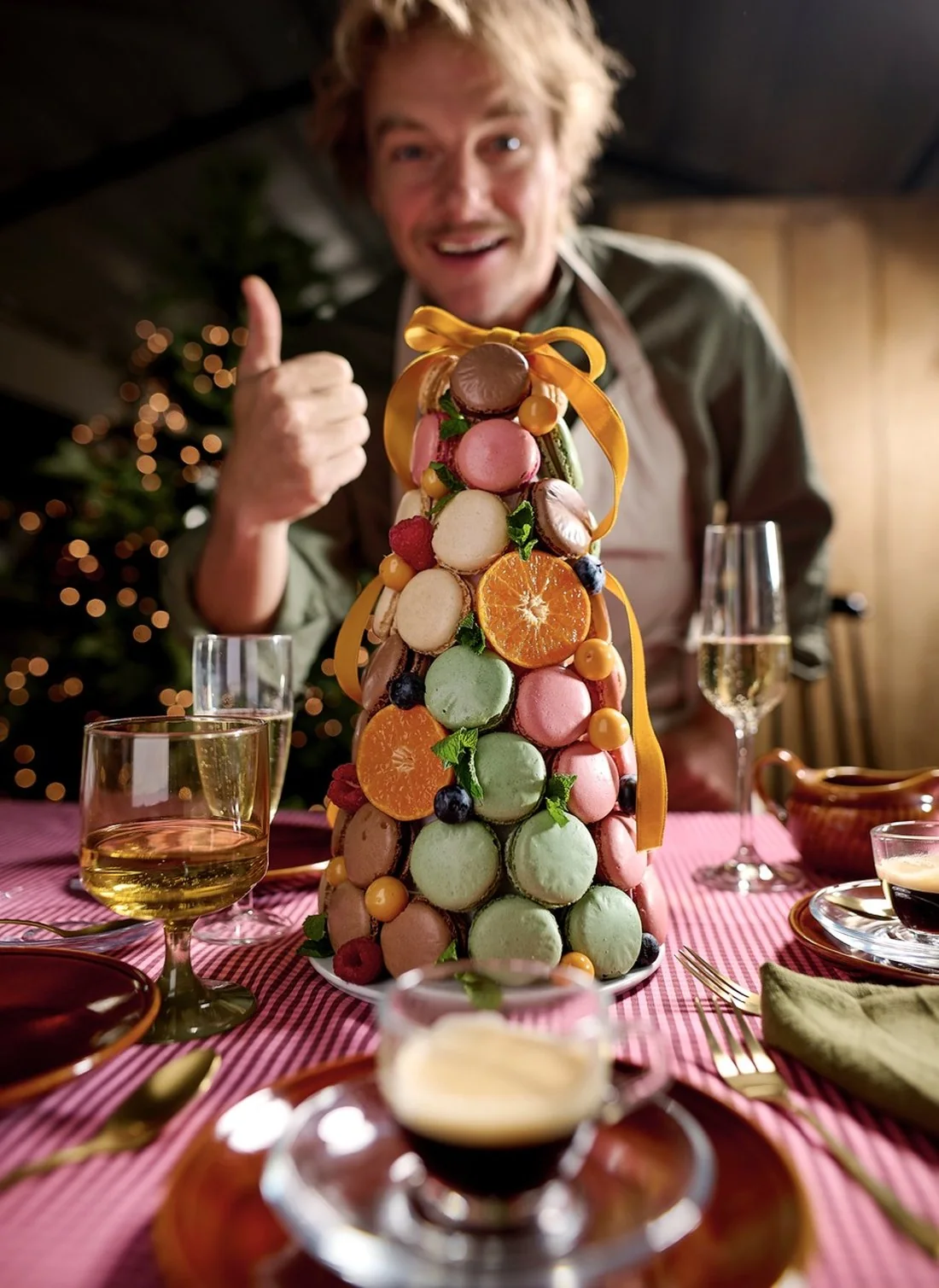 Shot on set: a man gives a thumbs up behind a macaron tower on a Christmas table