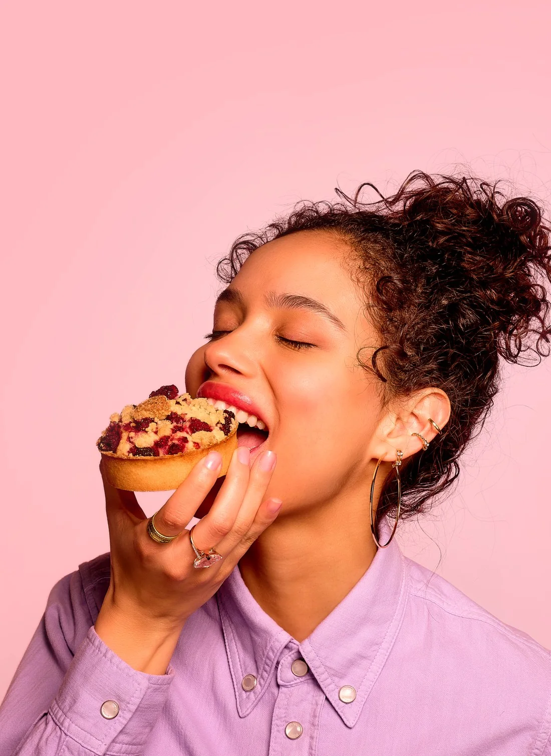 Shot on set: a young woman with her eyes closed bites into a crumble tart